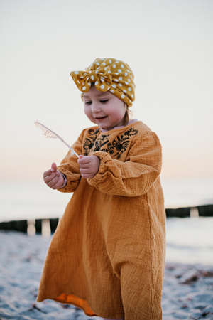 Little girl in oriental clothes walking along the beach at sunsetの写真素材