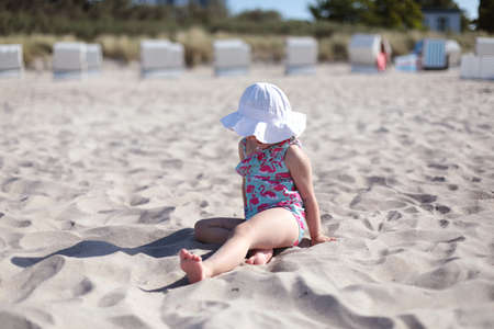 Little happy girl on white sand beach enjoying summer and vacation.の写真素材