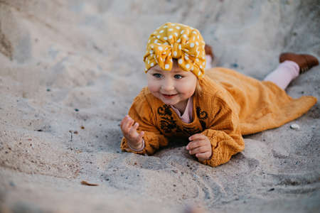 Little girl in oriental clothes walking along the beach at sunsetの写真素材