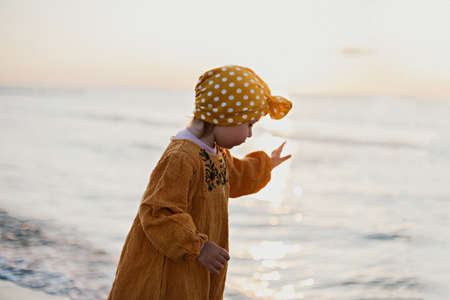Little girl in oriental clothes walking along the beach at sunsetの写真素材