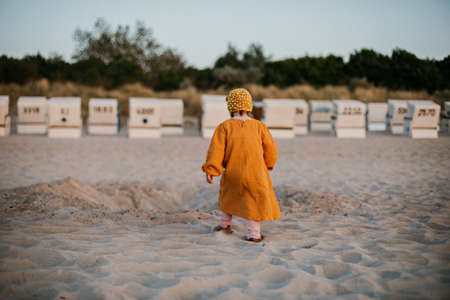 Little girl in oriental clothes walking along the beach at sunsetの写真素材
