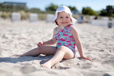 Little happy girl on white sand beach enjoying summer and vacation.の写真素材