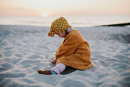 Little girl in oriental clothes walking along the beach at sunsetの写真素材