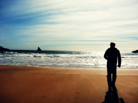 Silhouette of a man walking on the beachの写真素材