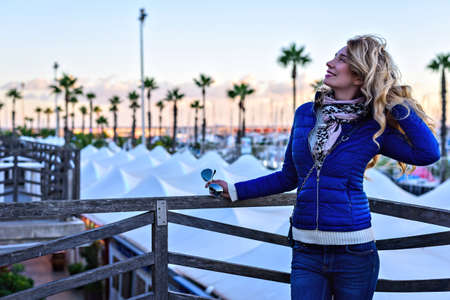 Girl in the Barcelona Port at sunset. Vintage city portrait of young stylish blonde woman having fun, travel aloneの写真素材