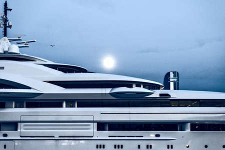 Yacht harbor close up at night. Blue background and full moon. Marina in bright moonlight. Luxury water transport nighttimeの写真素材
