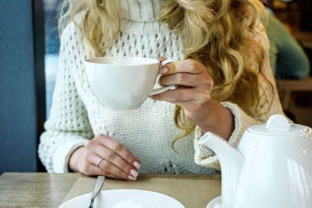 Woman drinking a Cup of tea in the restaurant. Winter leisure, cold weather, hot drink