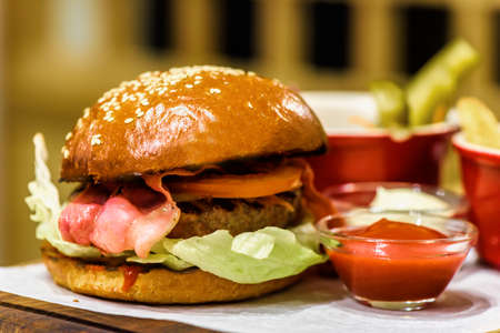 Homemade fresh burger with bacon on a wooden platterの写真素材