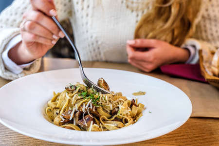 Woman eating Fresh delicious Mushroom pasta in a white plateの写真素材