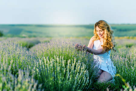 A girl in white dress picking flowers in the lavender field. Happy smileの写真素材