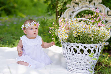Baby girl outdoors portrait. Sunny Green Summer background. Portrait of beautiful angel girl playing outsideの写真素材
