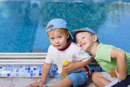Two adorable sibling kids having fun outdoors. Cute brothers playing together on sunny warm summer day. Brother love. Happy boys smiling on a sunny day by the pool. Brothers portraitの写真素材