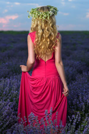 Beautiful Girl in a lavender Field at sunset. Pretty woman Provence style in a dress and flowers wreath. Beautiful blonde woman in the lavender field on sunset Amazing portraitの写真素材