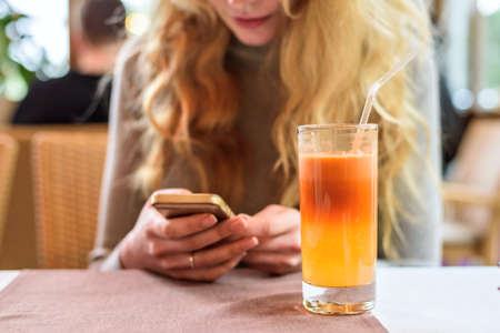 Fresh Apple Juice on the table in a restaurant. Girl chatting on the phone on backgroundの写真素材