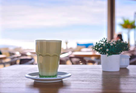 Latte at the beach. Iced Coffee  or frappe in a tall glass. Sea view background Barcelona Spainの写真素材