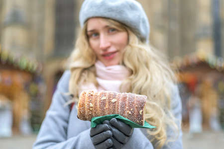Trdelnik national Czech dessert. Sweet bun. Woman eating tasty pastry. Soft focus views