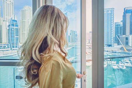 Woman in Dubai Marina, United Arab Emirates. Attractive lady wearing a long dress admiring Marina...