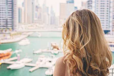 Woman in Dubai Marina, United Arab Emirates. Attractive lady wearing a long dress admiring Marina daylight viewsの写真素材