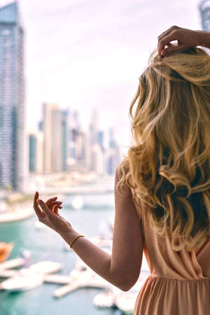 Woman in Dubai Marina, United Arab Emirates. Attractive lady wearing a long dress admiring Marina...