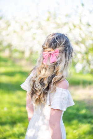 Woman in a blooming orchard at springtime. Enjoying sunny warm day. Retro style dress. Colorful spring moodsの写真素材