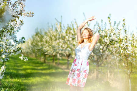 Happy Woman in an orchard at springtime. Enjoying sunny warm day.の写真素材