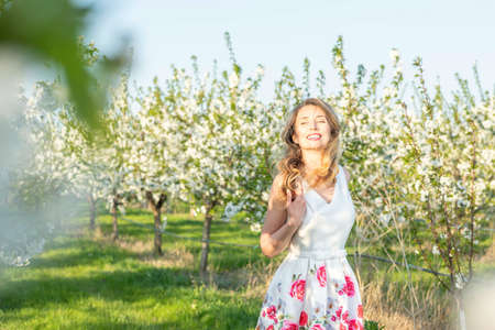 Happy Woman in an orchard at springtime. Enjoying sunny warm day.の写真素材
