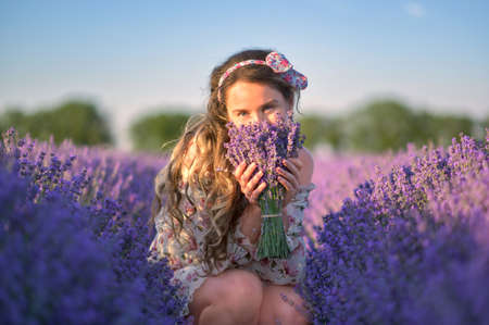 Woman in lavender field enjoying summer day. Beatiful purple floral meadowの写真素材