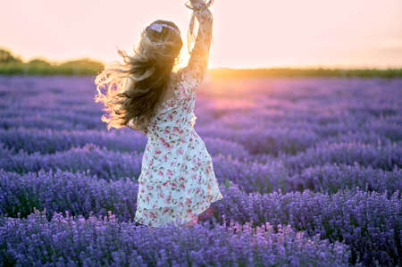 Happy woman dancing in a lavender field at sunset. Beautiful flowers meadow. Summer sunset colorfulの写真素材