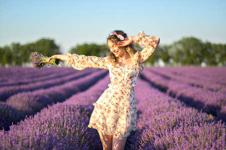 Happy woman dancing in a lavender field at sunset. Beautiful flowers meadowの写真素材