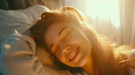 Beautiful young woman lying on the bed at home and smiling.の素材