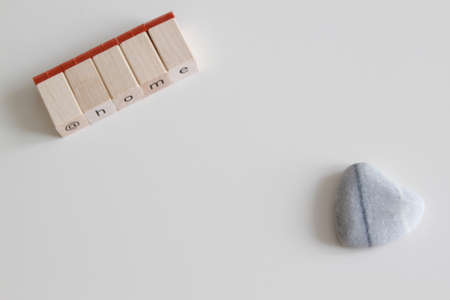 at home home in single wooden letters and heart of stone on white tableの写真素材