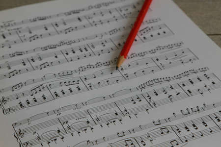 Music notes for piano and cello with red pencil on wooden tableの写真素材