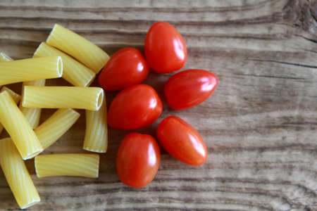 Raw Penne Pasta with Tomatoes on wooden tableの写真素材