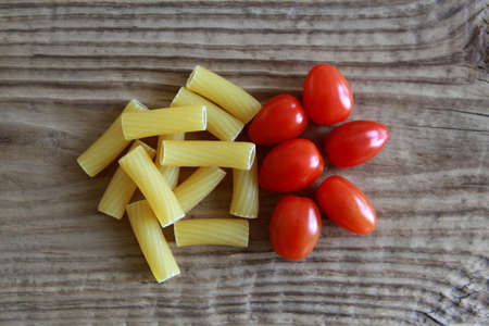 Raw Penne Pasta with Tomatoes on wooden tableの写真素材