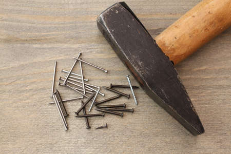 Hammer with nails on wood background