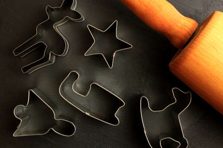 Christmas cookie cutters with rolling pin on black backgroundの写真素材