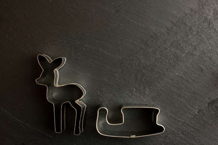 Cookie cutters deer and sleigh on black backgroundの写真素材