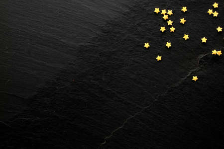 Small golden sugar stars on black background with space for your messageの写真素材
