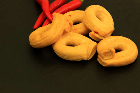 Delicious italian snack tarallini with red peppers on black backgroundの写真素材