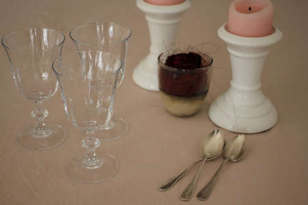 Romantic table with candles, rose, empty wine glasses and silver coffee spoonsの写真素材