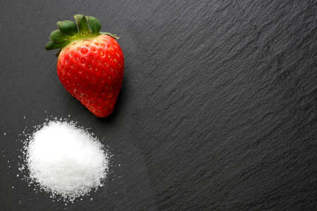 Strawberry with crystal sugar on black slate backgroundの写真素材
