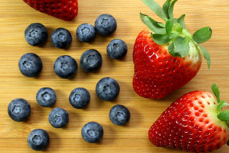 Red, ripe strawberries and blueberries on bamboo backgroundの写真素材