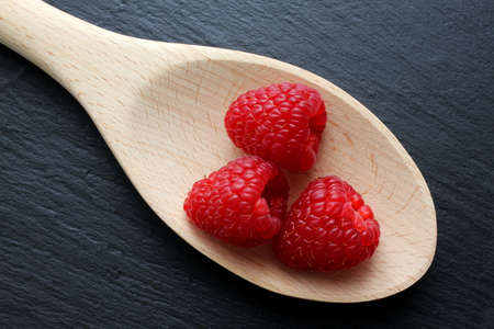 Raspberries on wooden kitchen trowel on slate boardの写真素材