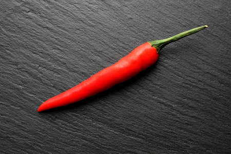 Red hot chilli pepper on modern looking slate boardの写真素材