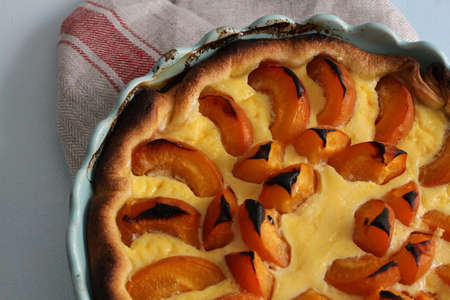 Homemade apricot pie in blue baking pan on linen kitchen towelの写真素材