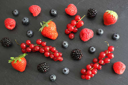 Fresh berries on dark board, top view