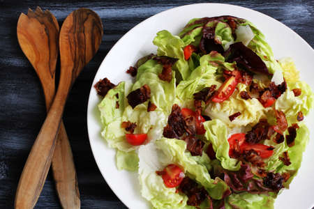 Red lettuce salad with tomatoes and fried bacon in white plateの写真素材