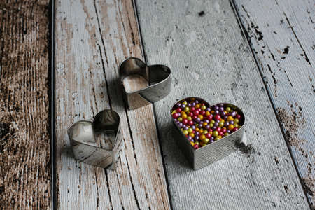 Heart shape pastry cutter with colorful sugar pearls on wooden tableの写真素材