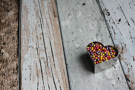 Heart shape pastry cutter with colorful sugar pearls on wooden tableの写真素材