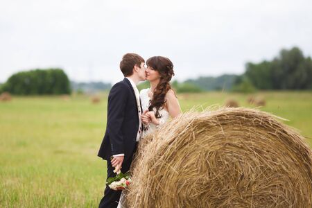 Bride and groom near hay on a rural fieldの写真素材